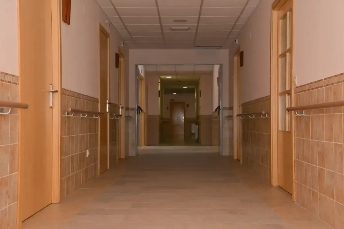 Pasillo interior vacío con paredes beige, suelo de baldosas y puertas a ambos lados.