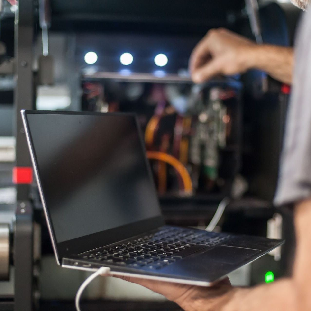 Un homme tient un ordinateur portable avec un cordon branché dessus
