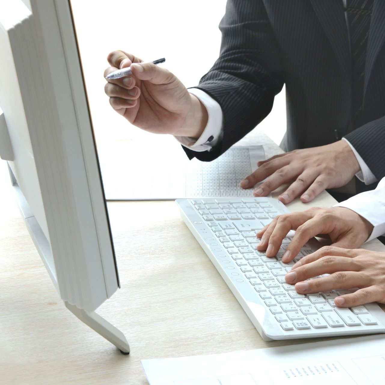 Un homme pointe un écran d'ordinateur tandis qu'un autre homme tape sur un clavier
