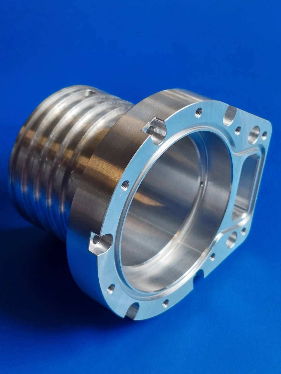 Bearbeitetes Aluminiumbauteil mit Innenbohrung, Aussengewinde und Montageflansch.