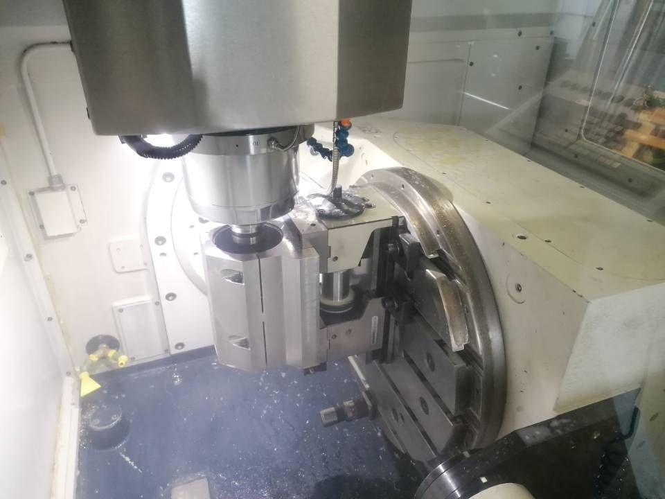 Eine CNC-Maschine mit Drehtisch und angebrachtem Schneidwerkzeug zur Bearbeitung eines Metallteils.