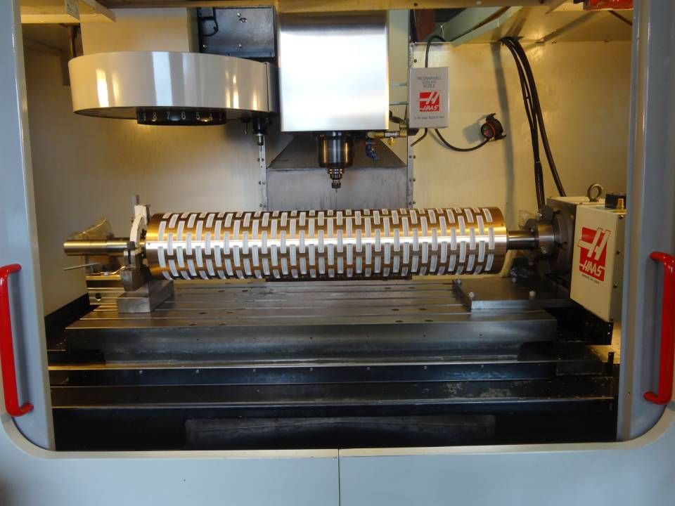 CNC-Maschine schneidet eine Metallwalze mit einem komplexen Muster.