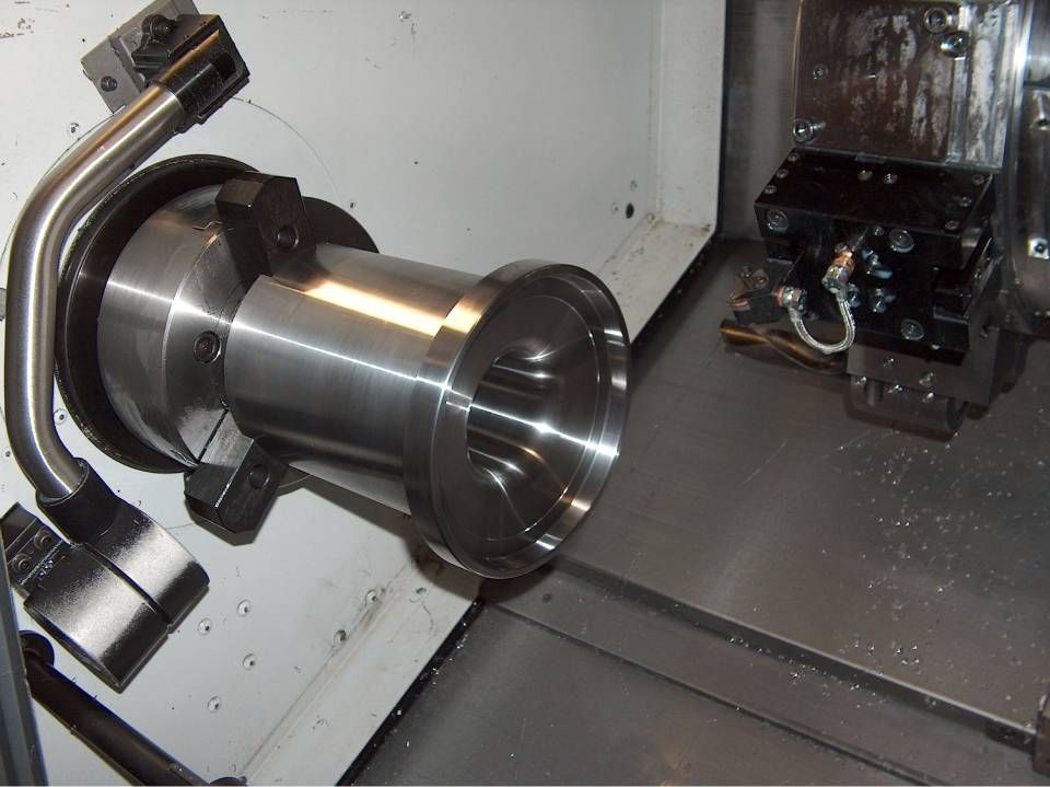 Ein auf einer CNC-Drehmaschine bearbeitetes Metallbauteil. Das Teil ist in einem Spannfutter eingespannt und hat eine konische Innenform.