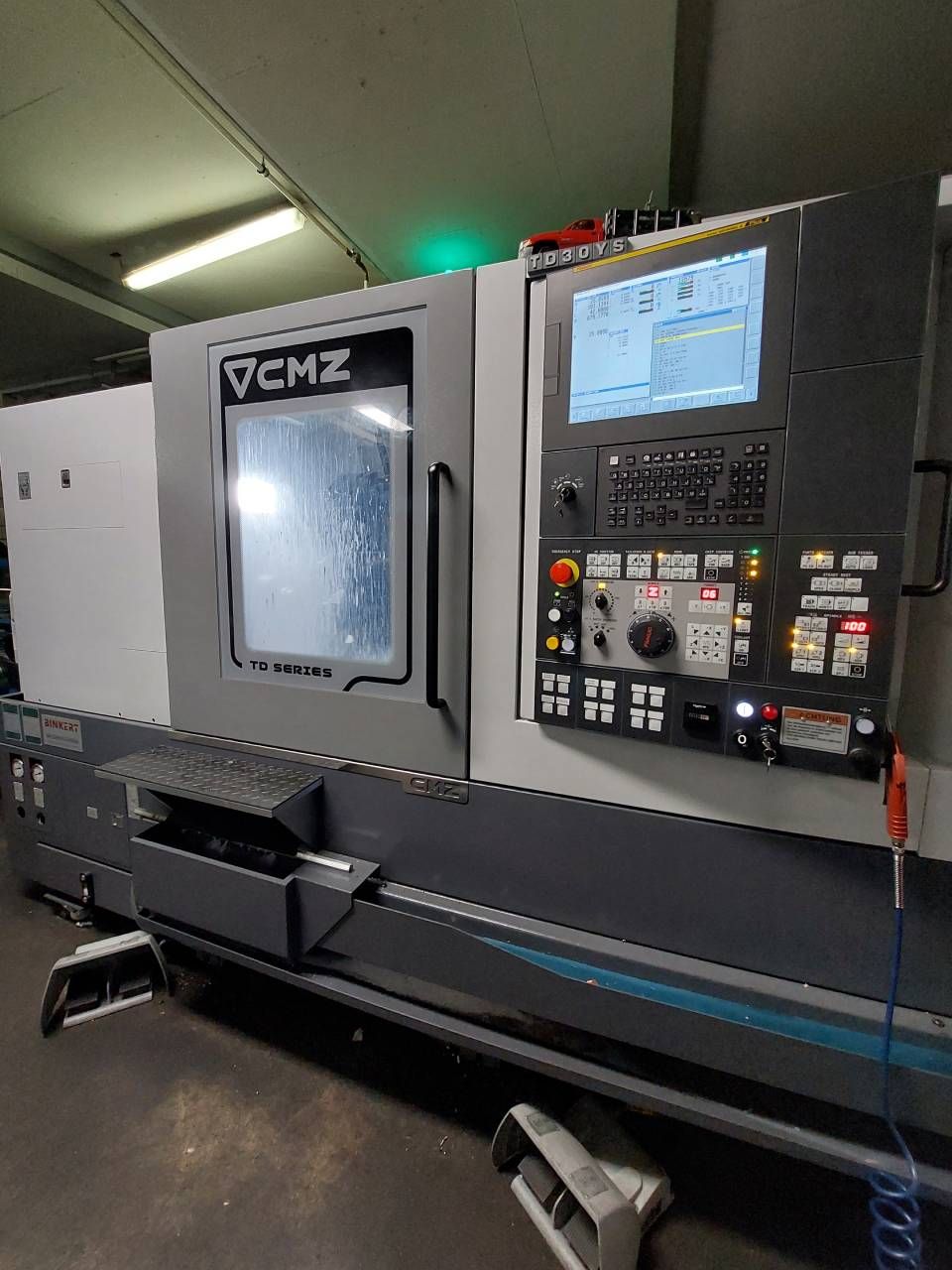 CMZ CNC-Drehmaschine mit Bedienfeld und geschlossenem Arbeitsbereich. Grau, Schwarz und Blau. Industrielle Ausführung.