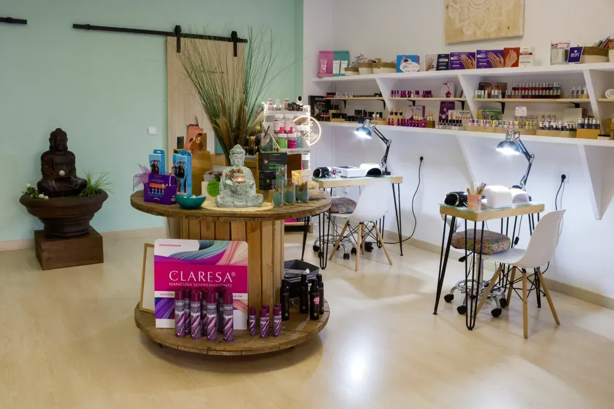 Un salón de manicura con un expositor de carretes de madera, una estatua de Buda y dos puestos de manicura