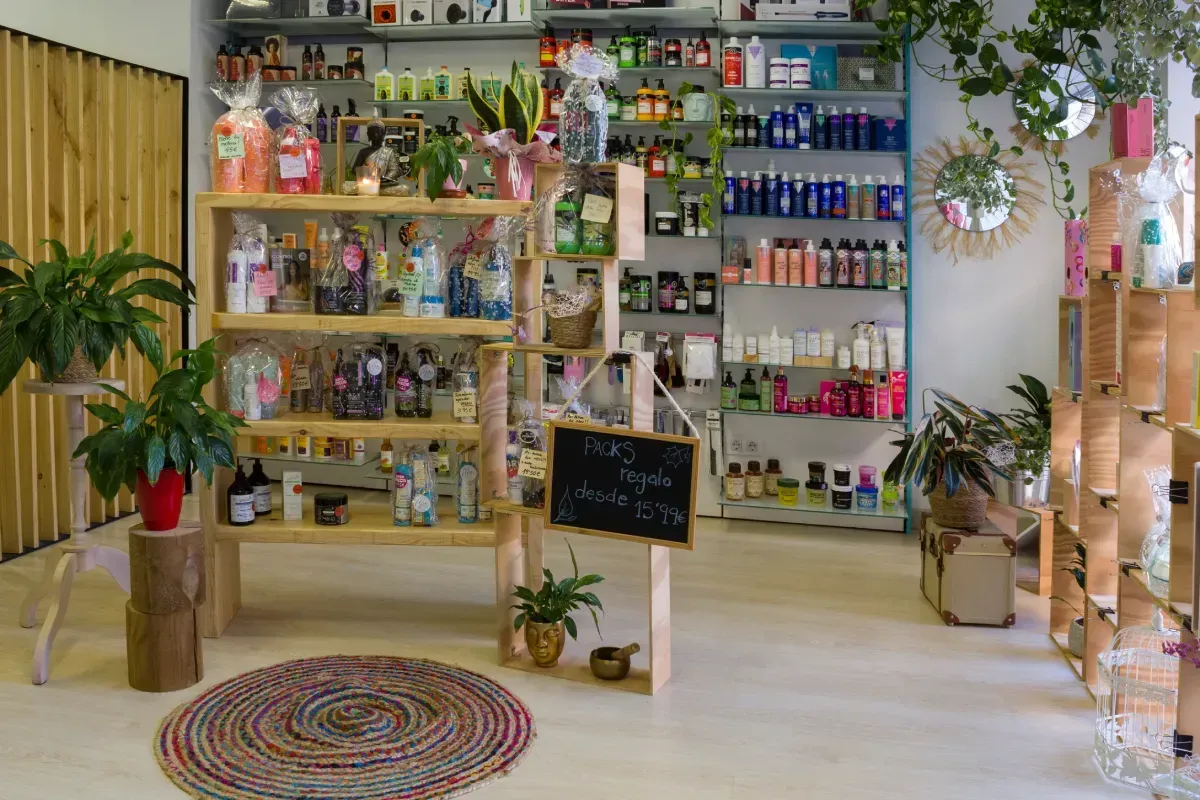 Una tienda con estanterías de madera que exhiben diversos productos de belleza, plantas, una alfombra redonda
