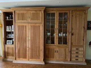 Einbauschränke aus Holz in einem Raum. Inklusive Stauraum, geschlossenen Türen, Glasschrank mit Geschirr und Schubladen.