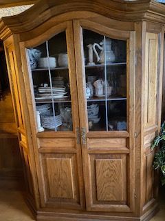 Hölzerne Vitrine mit Glastüren, in der weißes Geschirr und Teetassen ausgestellt sind.