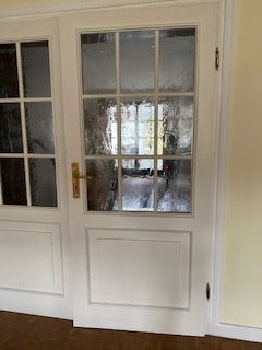 Weiße Türen mit Glasscheiben, goldenen Beschlägen und einem Blick nach draußen.