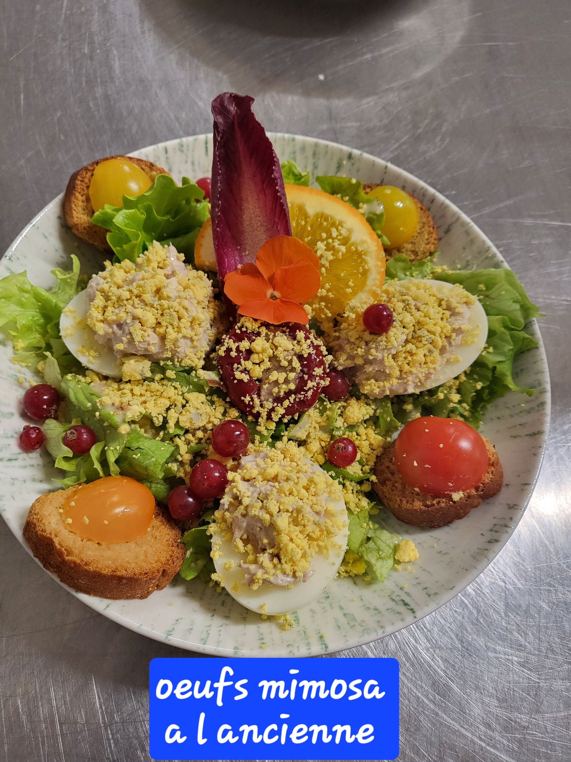 Assiette d'amuse-gueules colorés assortis, comprenant des œufs mimosa, de la laitue et des tomates cerises sur un plat.