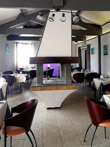 Intérieur d'un restaurant vide avec des tables, des chaises et une cheminée centrale sous une hotte.