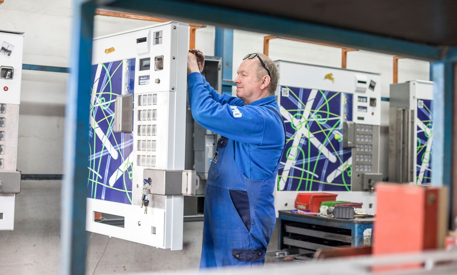 Ein Mann in einem blauen Overall arbeitet in einer Fabrik an einer Maschine.