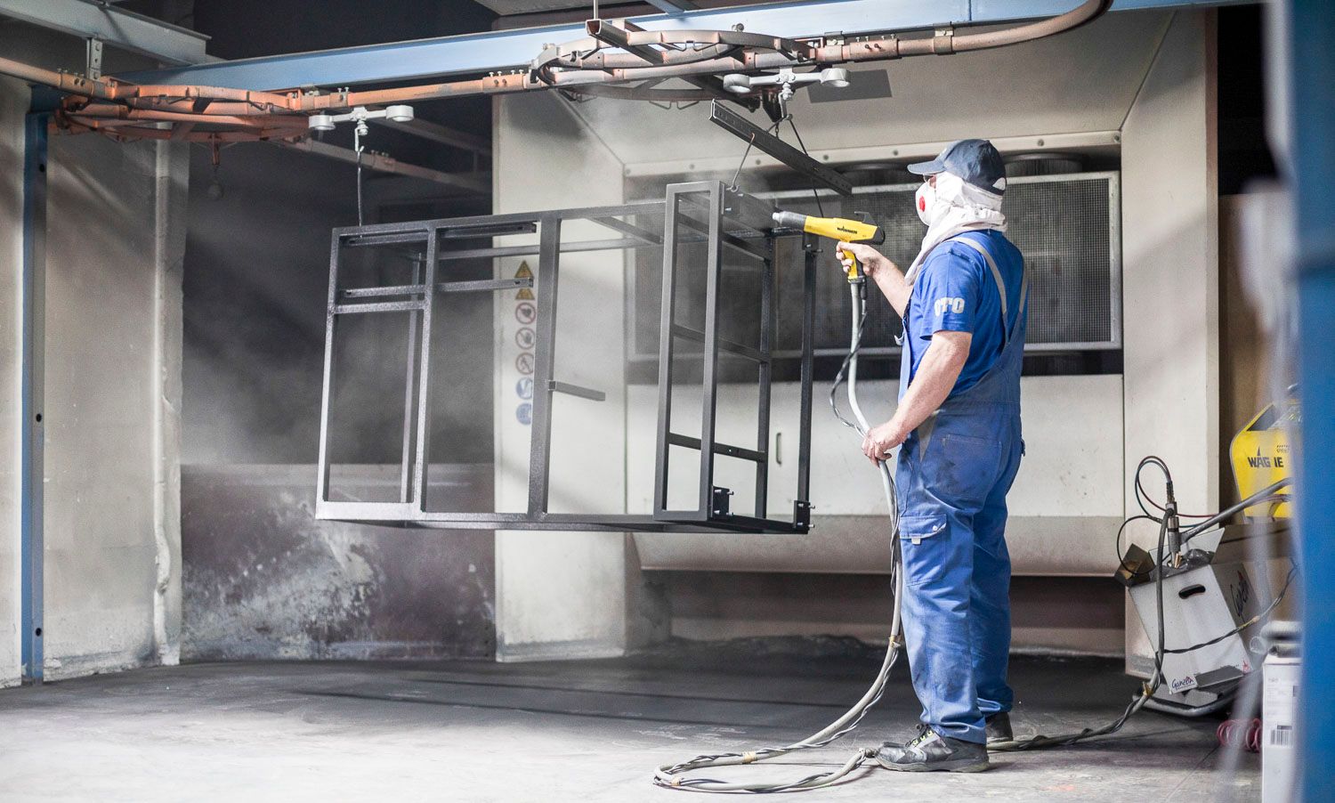 Ein Mann bemalt in einer Fabrik ein Stück Metall.