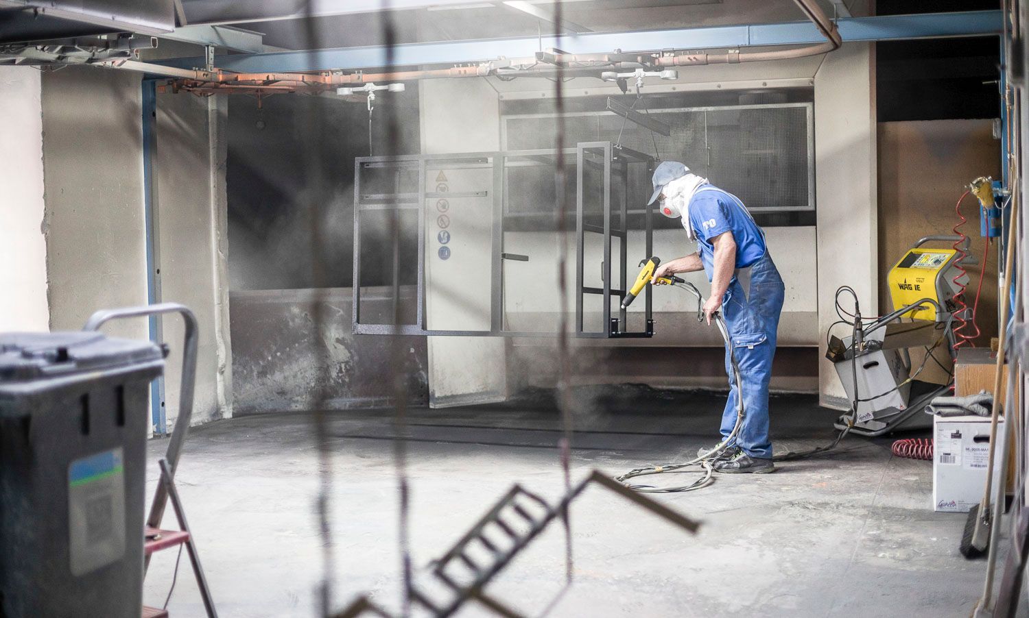 Ein Mann streicht eine Metallkonstruktion in einer Garage.