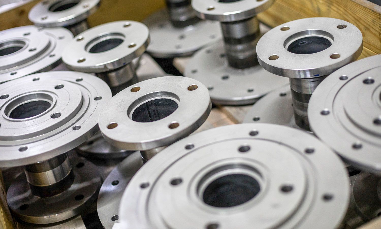 In einer Kiste liegen mehrere Metallteile übereinander gestapelt.