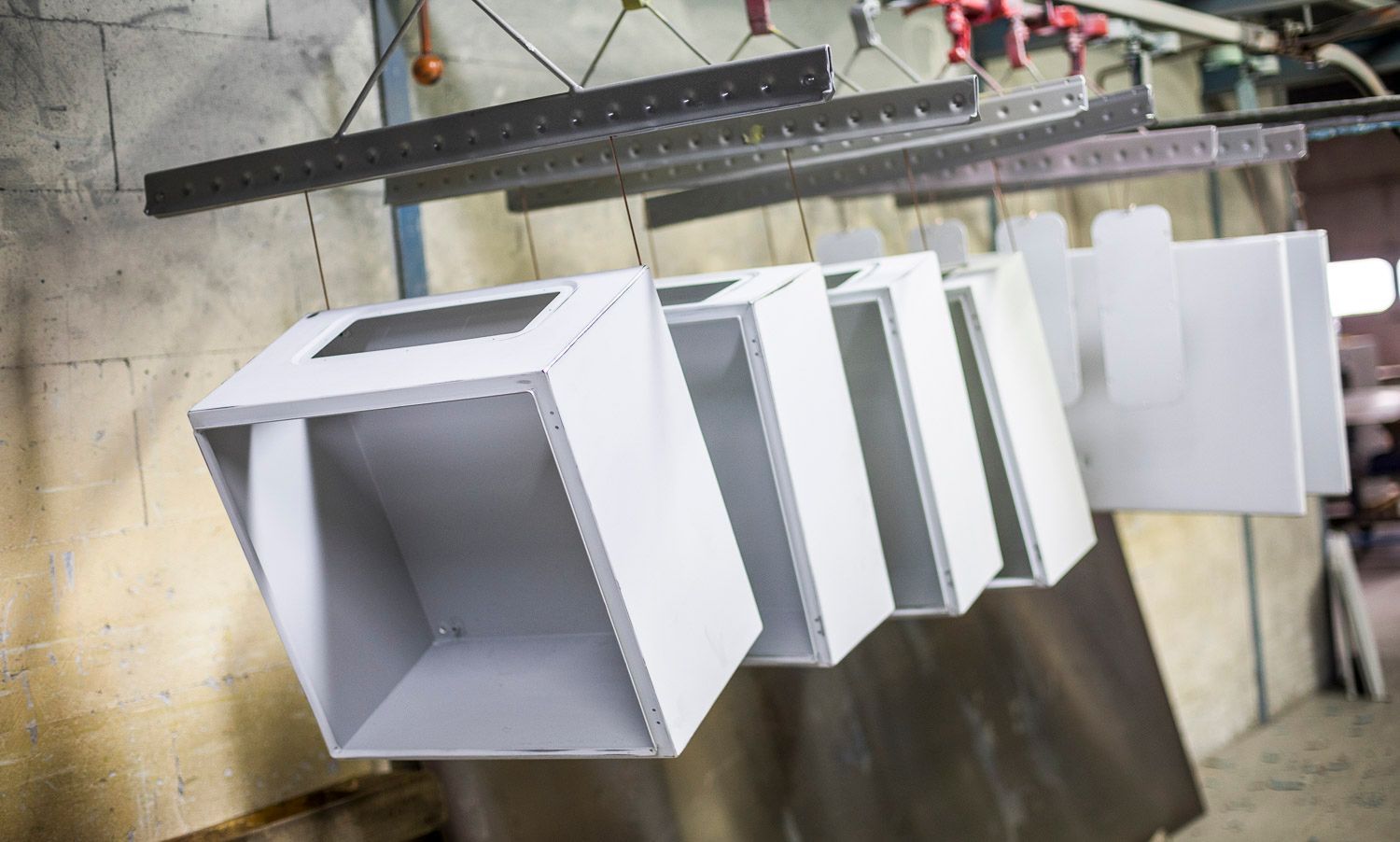 Eine Reihe weißer Kästen hängt von der Decke einer Fabrik.