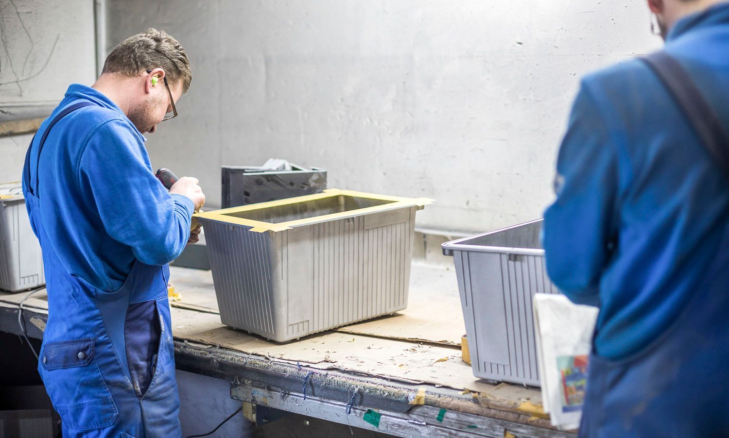 Zwei Männer arbeiten an einem Tisch in einer Fabrik.