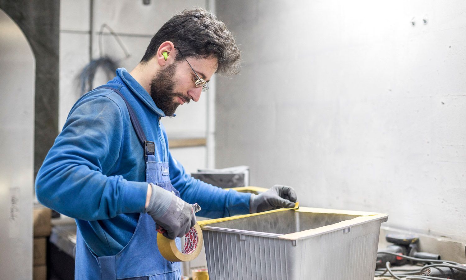 Ein Mann misst einen Metallbehälter mit einem Maßband.