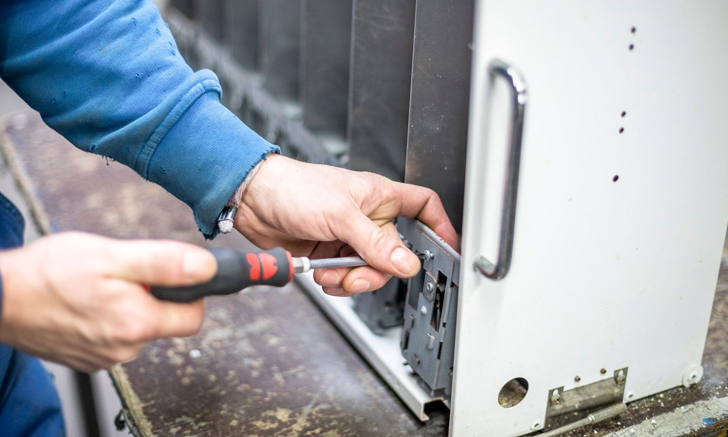 Ein Mann arbeitet mit einem Schraubenzieher an einer Maschine.