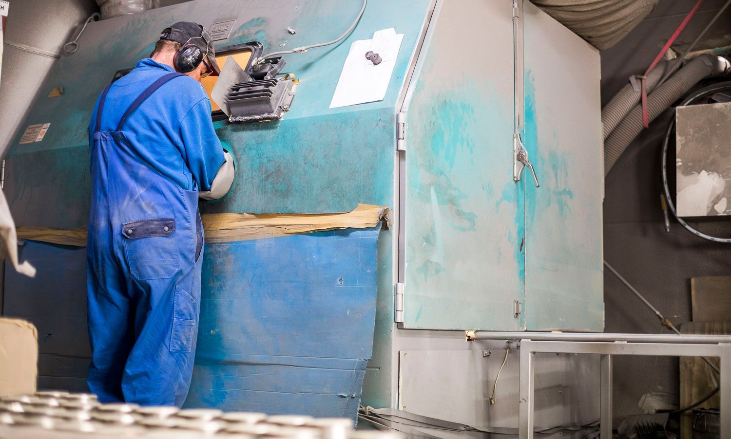 Ein Mann im blauen Overall arbeitet in einer Fabrik an einer Maschine.