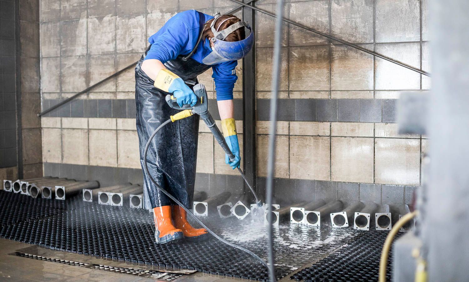 Eine Frau reinigt eine Wand mit einem Hochdruckreiniger.