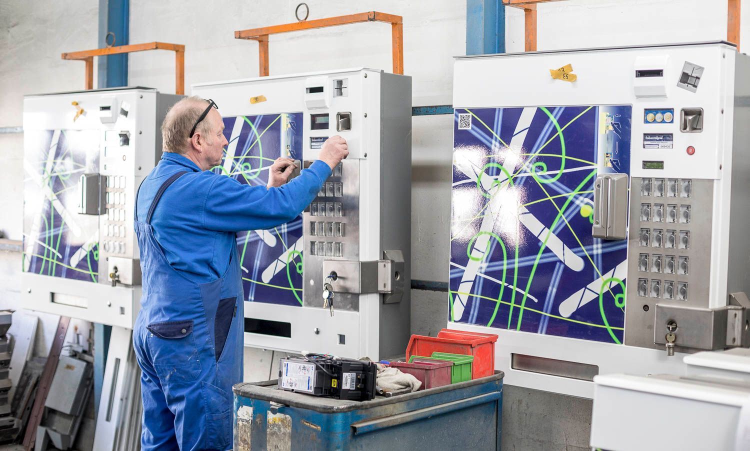 Ein Mann in einem blauen Overall arbeitet in einer Fabrik an einer Maschine.