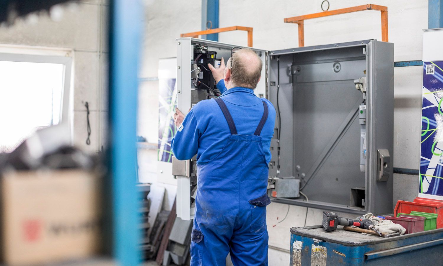 Ein Mann in einem blauen Overall arbeitet in einer Fabrik an einer Maschine.