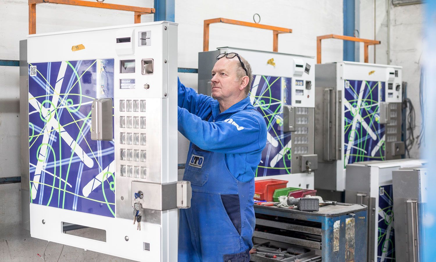 Ein Mann in einem blauen Overall arbeitet in einer Fabrik an einer Maschine.