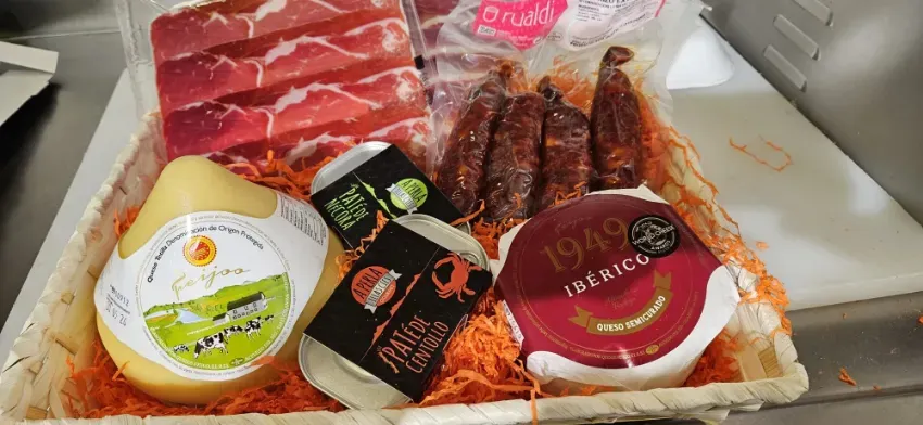 Surtido de embutidos y quesos envasados en una bandeja refrigerada con etiquetas rojas y blancas.