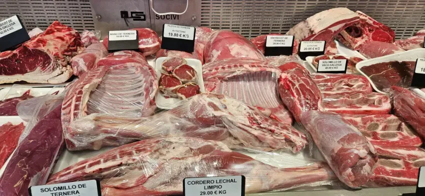 Exhibidor de carnicería con surtido de cortes de carne roja y costillas crudas en bandejas con etiquetas de precio.