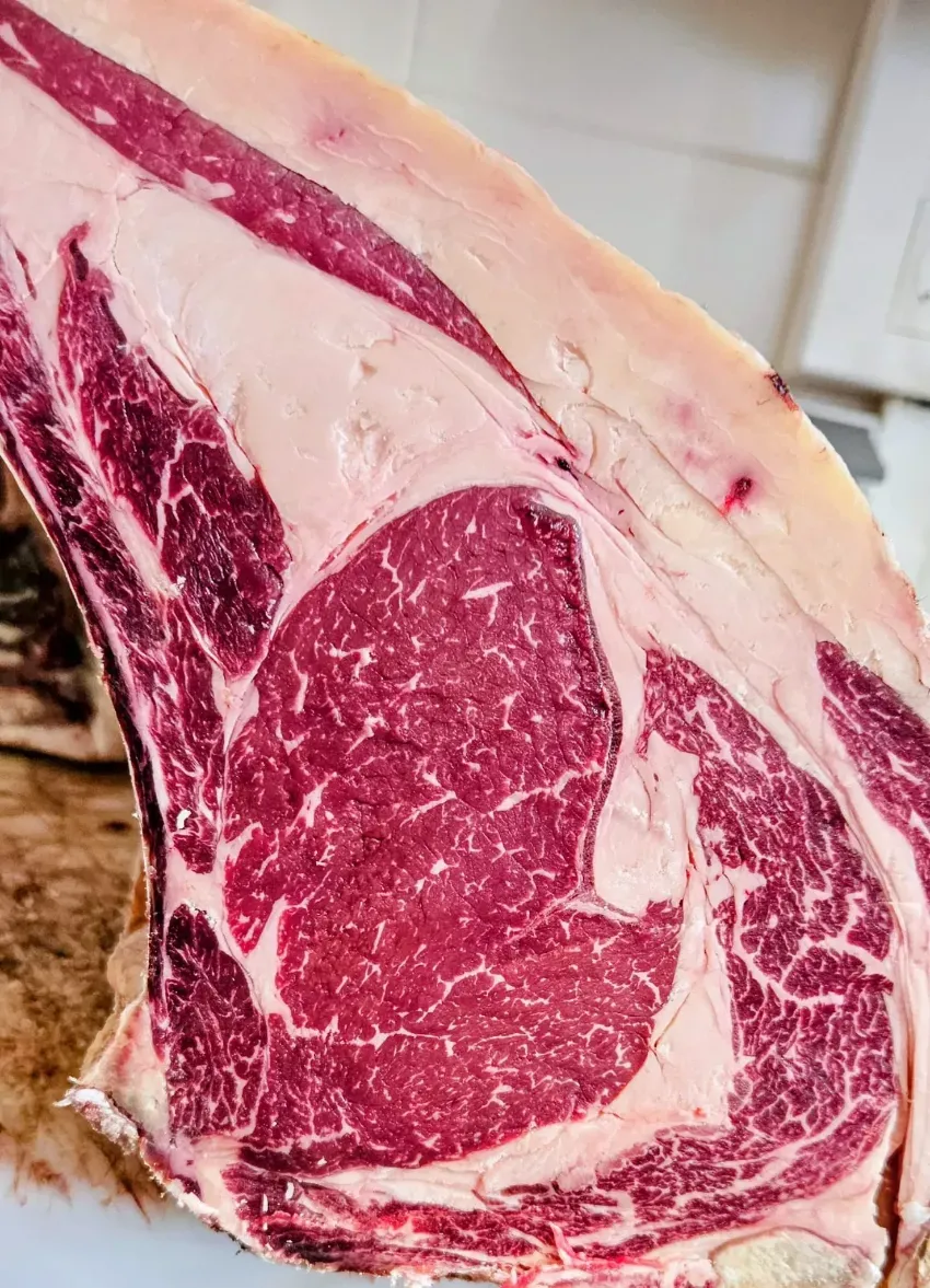Filete de ternera crudo veteado con una gruesa capa de grasa sobre el mostrador de una carnicería.