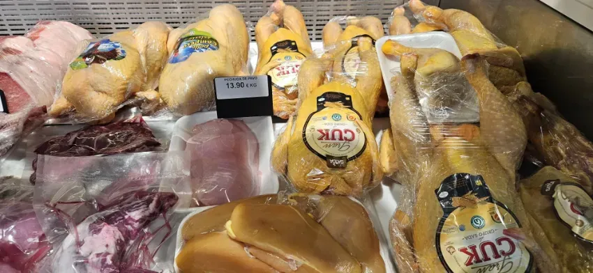 Carne y aves crudas envasadas, expuestas en una vitrina refrigerada.
