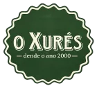 Logotipo de insignia verde festoneada con la inscripci&oacute;n &ldquo;O Xur&eacute;s&rdquo; y &ldquo;dende o ano 2000&rdquo; en texto color crema.