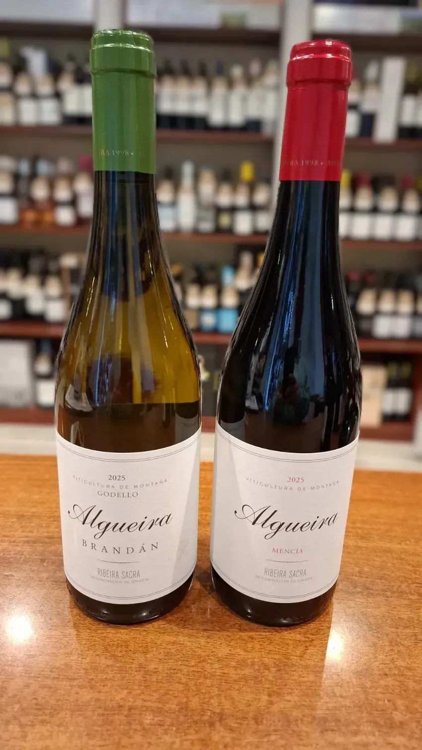 Dos botellas de vino sobre una mesa de madera, una con tapón verde y otra con tapón rojo.