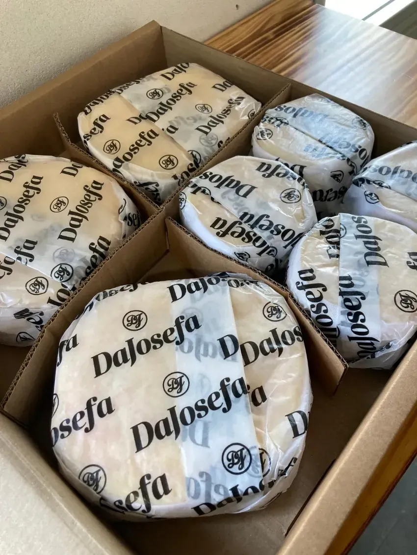 Docenas de pasteles envueltos en una caja de cartón sobre una mesa de madera.