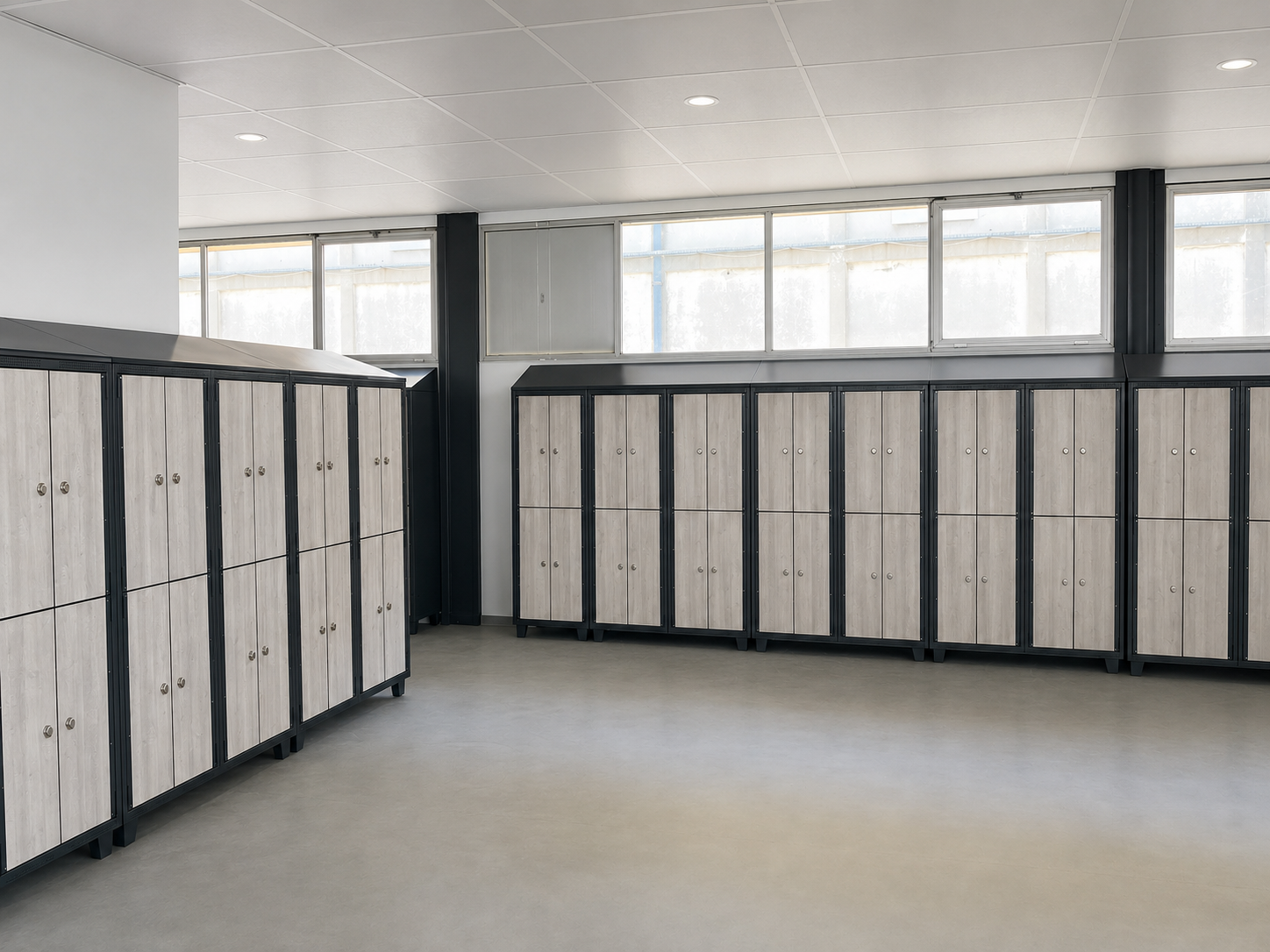 Des rangées de casiers scolaires blancs dans un vestiaire lumineux et vide avec de grandes fenêtres