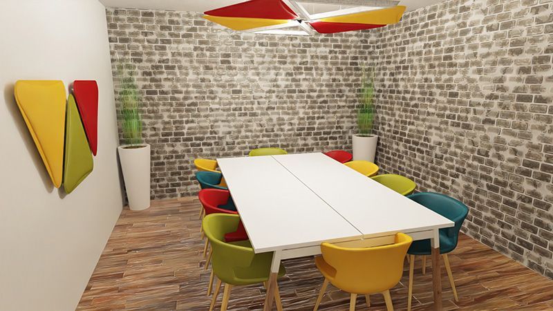 Salle de réunion avec mur en brique, table blanche et sièges colorés