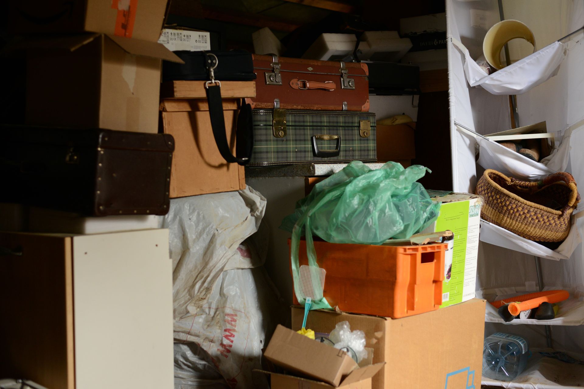 Des étagères et valises dans une pièce débordante d’objets divers et d’affaires personnelles