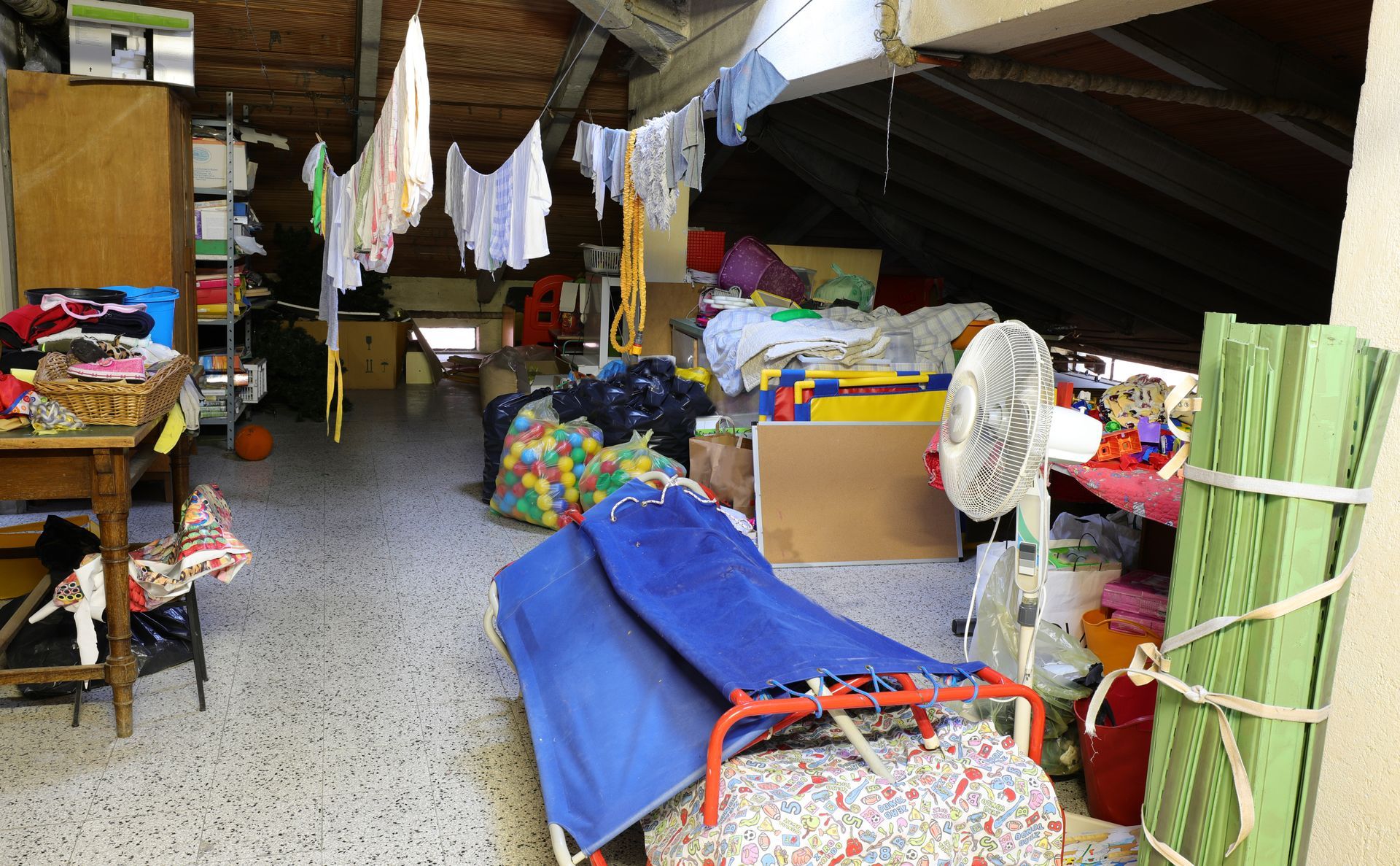 Un grenier rempli de vêtements, jouets et objets stockés en désordre