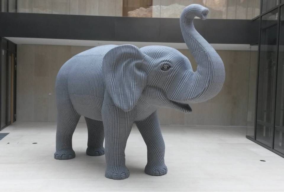 Eine grosse, graue Elefantenskulptur aus einzelnen Plastikbausteinen, die mit erhobenem Rüssel dasteht.