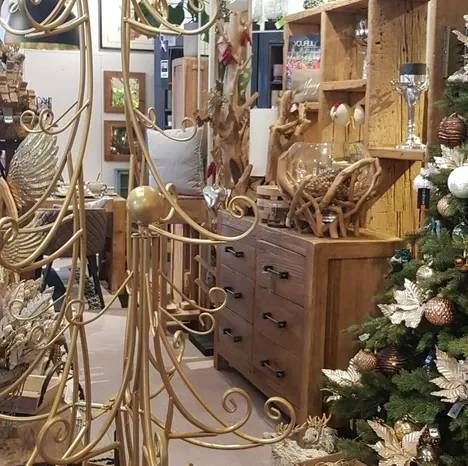 Nahaufnahme von Skulpturen aus Golddraht in einem Einzelhandelsgeschäft neben einer hölzernen Kommode und einem Weihnachtsbaum.