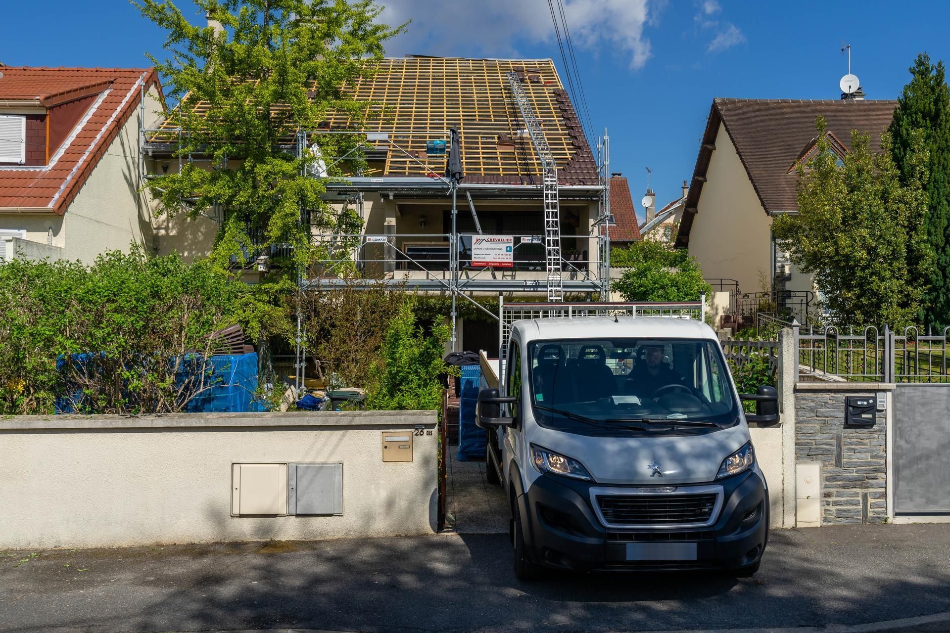 Rue résidentielle avec une camionnette garée devant une maison en rénovation.