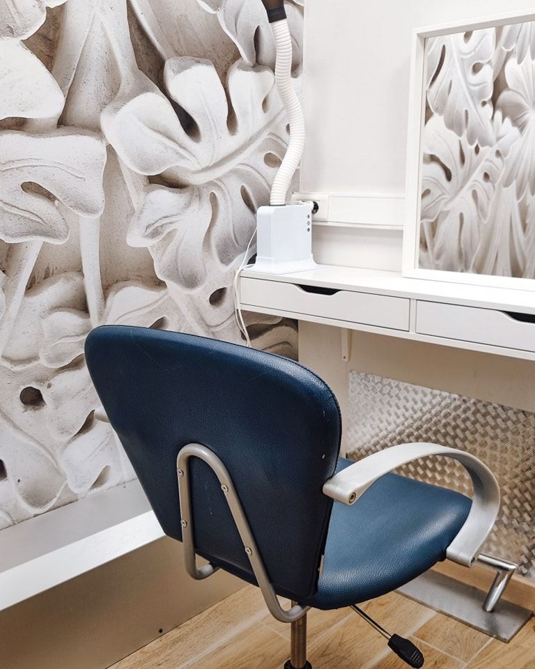 Un fauteuil bleu devant une glace dans le salon de coiffure.