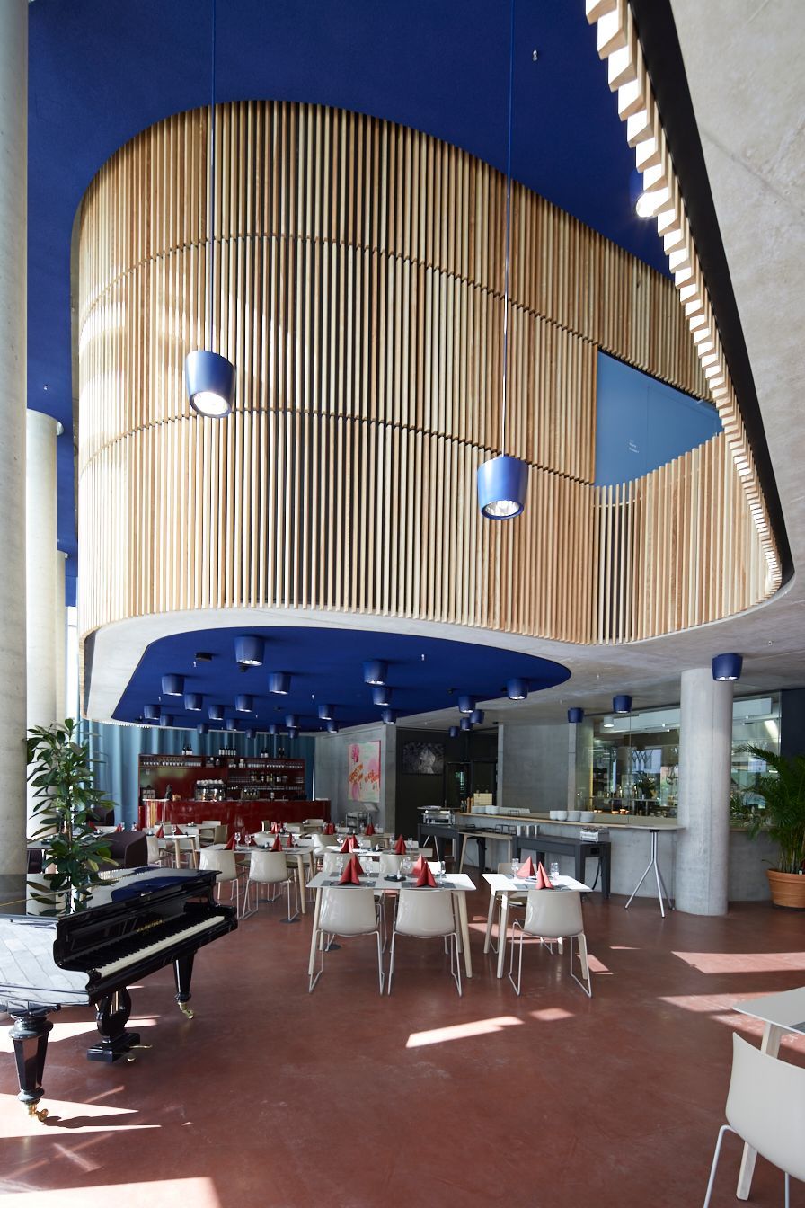 Essbereich mit blauer Decke, Holzvertäfelung, Tischen, Stühlen und einem Flügel.