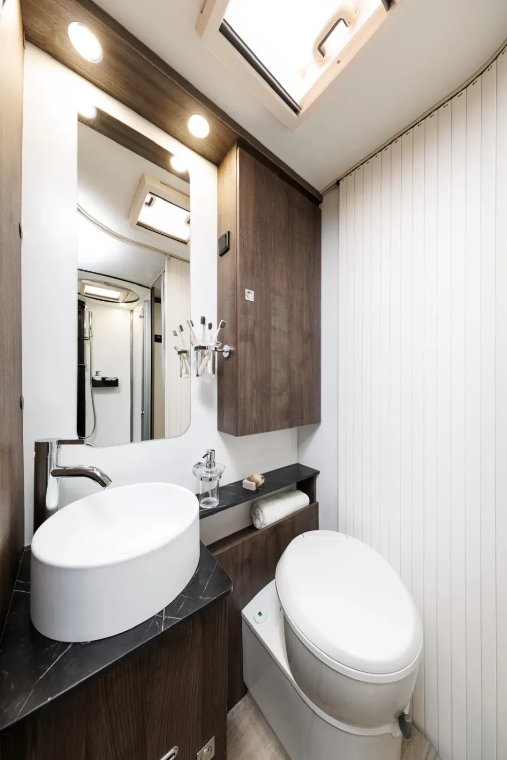 Baño pequeño y moderno para autocaravana, con lavabo ovalado blanco, tocador, inodoro,