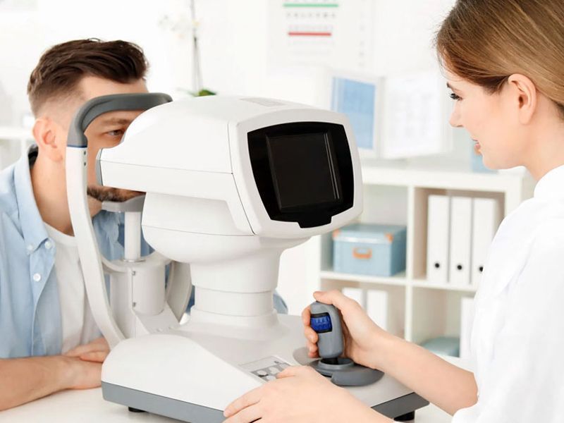 Un hombre se somete a un examen de la vista por parte de un médico con un aparato autorrefractómetro en un consultorio.
