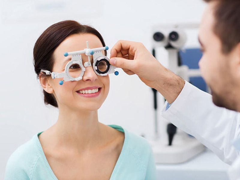 Mujer sonriendo durante el examen ocular, el médico ajusta la lente en la clínica.