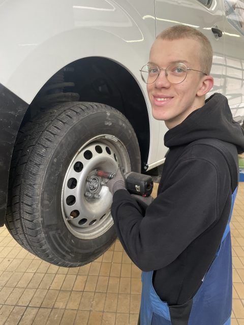 Ein junger Mann arbeitet am Rad eines Autos