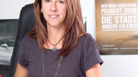Eine Frau sitzt vor einem Peugeot-Poster