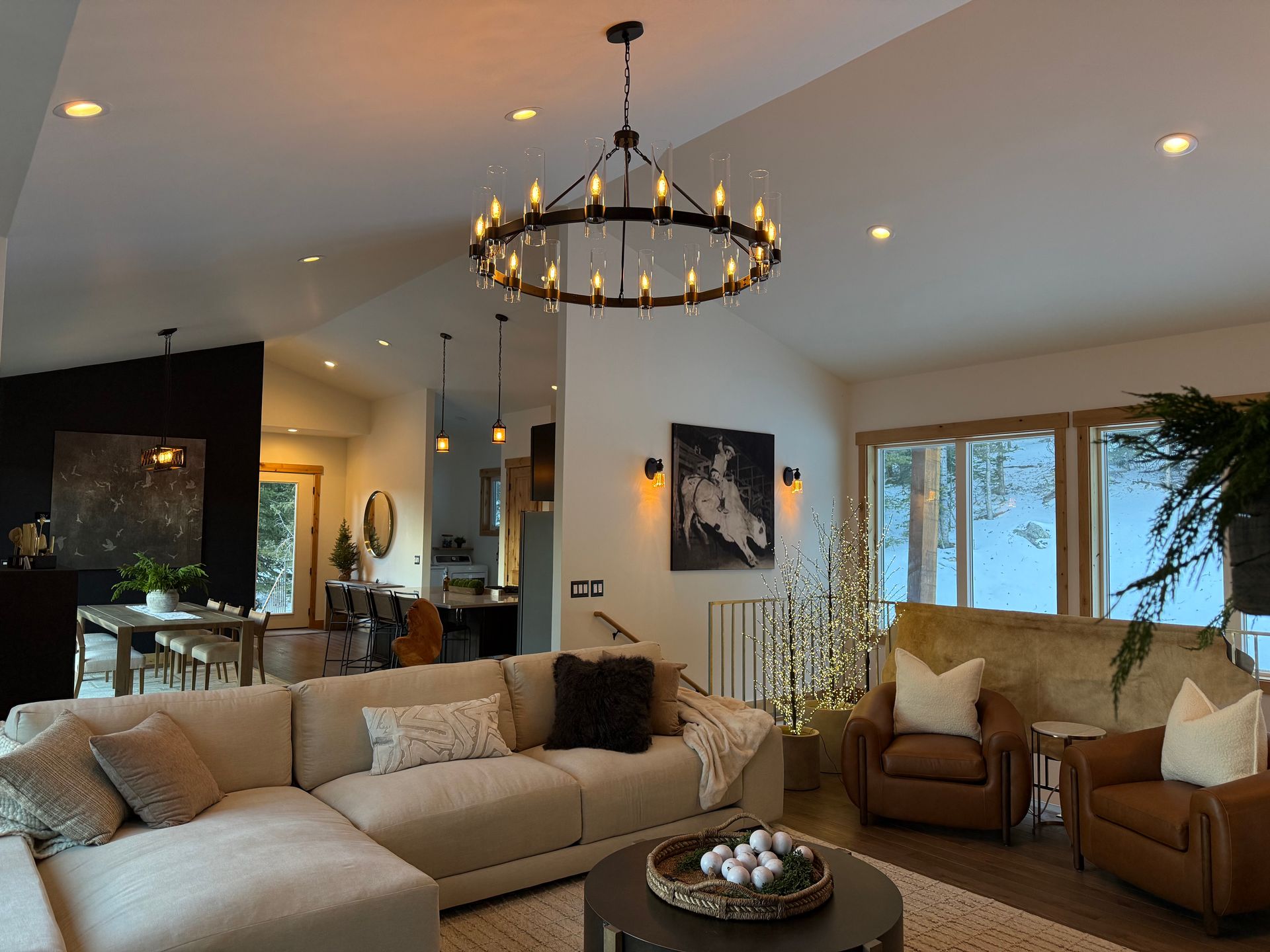 Cozy living room with a large chandelier, sectional sofa, and leather armchairs, decorated for the holidays.